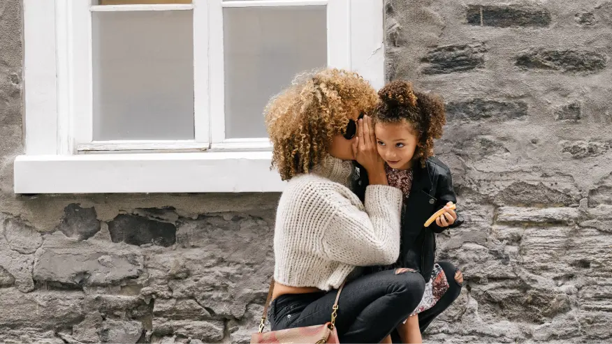 lady whispering in childs ear